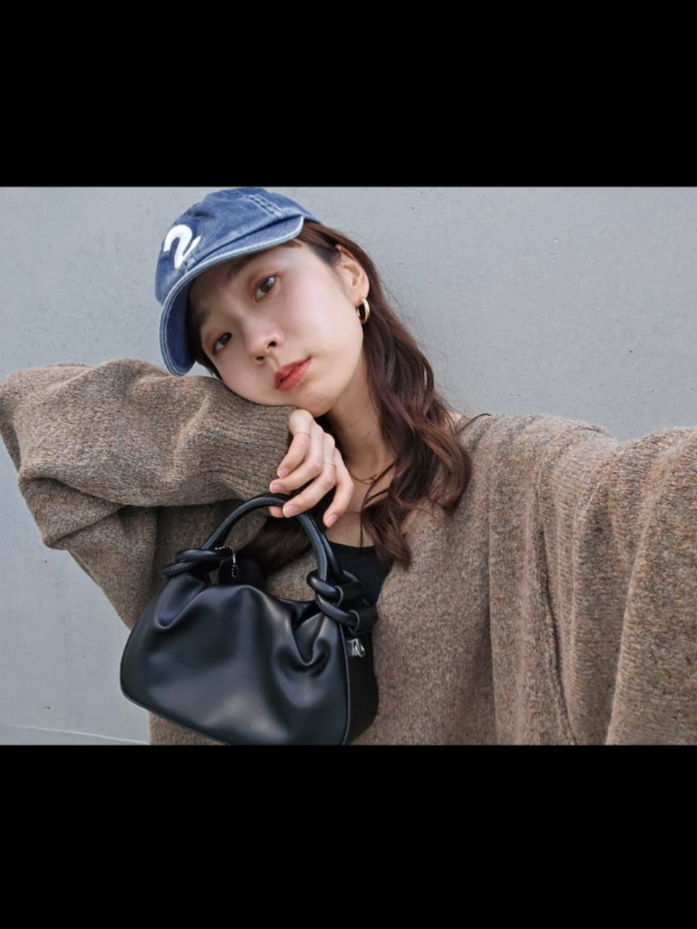 ブルー系のデニムパンツ、ブラウン系のカーディガン/ボレロ、ブラック系のハンドバッグを着用したレディースの秋コーディネートの3枚目の写真