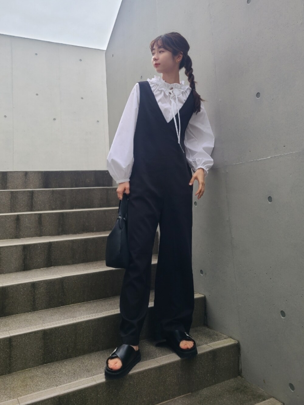 ブラック系のサンダル、ホワイト系のシャツ/ブラウス、ブラック系のサロペット/オーバーオールを着用したレディースの春コーディネートの2枚目の写真