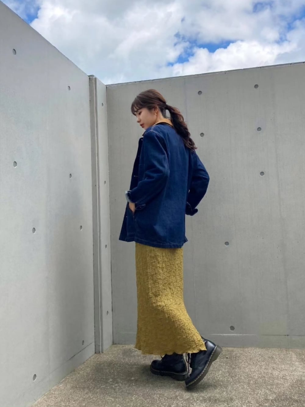 ブルー系のデニムジャケット、グリーン系のスカート、ブラック系のブーツを着用したレディースの秋コーディネートの3枚目の写真