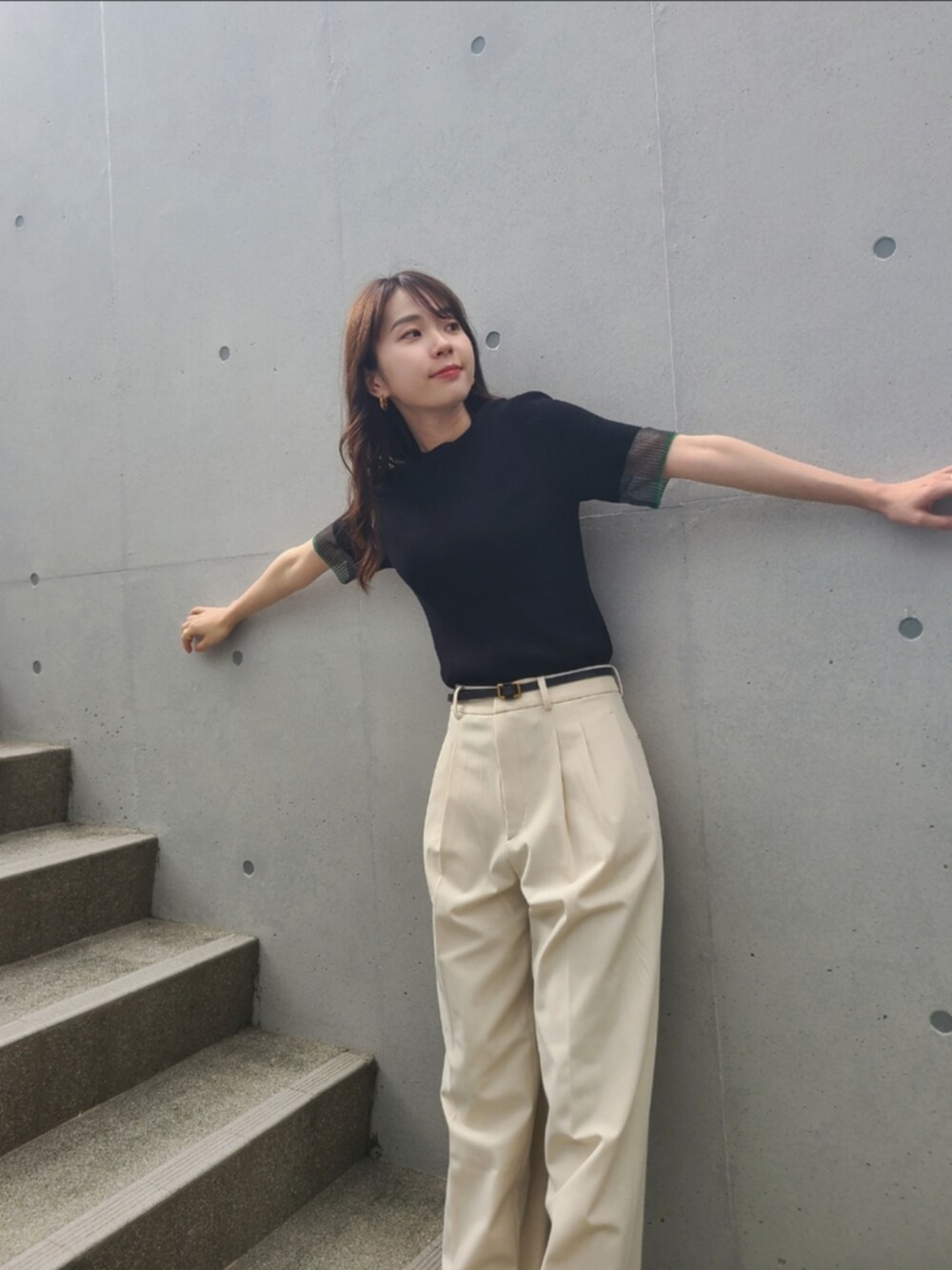 ブラック系のニット/セーター、ホワイト系のパンツ、ゴールド系のピアス（両耳用）を着用したレディースの夏コーディネートの2枚目の写真