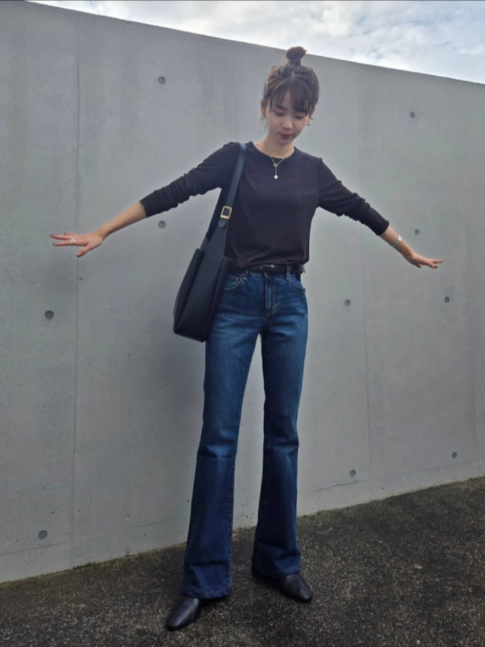 ブラック系のTシャツ/カットソー、ブルー系のデニムパンツ、ブラック系のブーツを着用したレディースの秋コーディネートの3枚目の写真