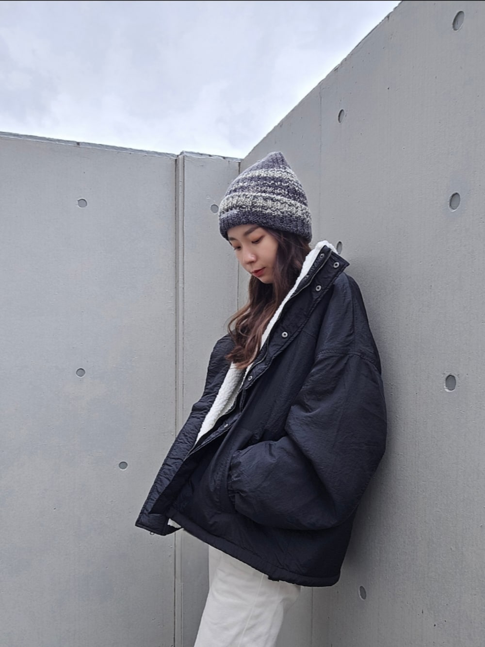 ブラック系のブルゾン、ホワイト系のデニムパンツ、ブラック系のブーツを着用したレディースの秋コーディネートの2枚目の写真