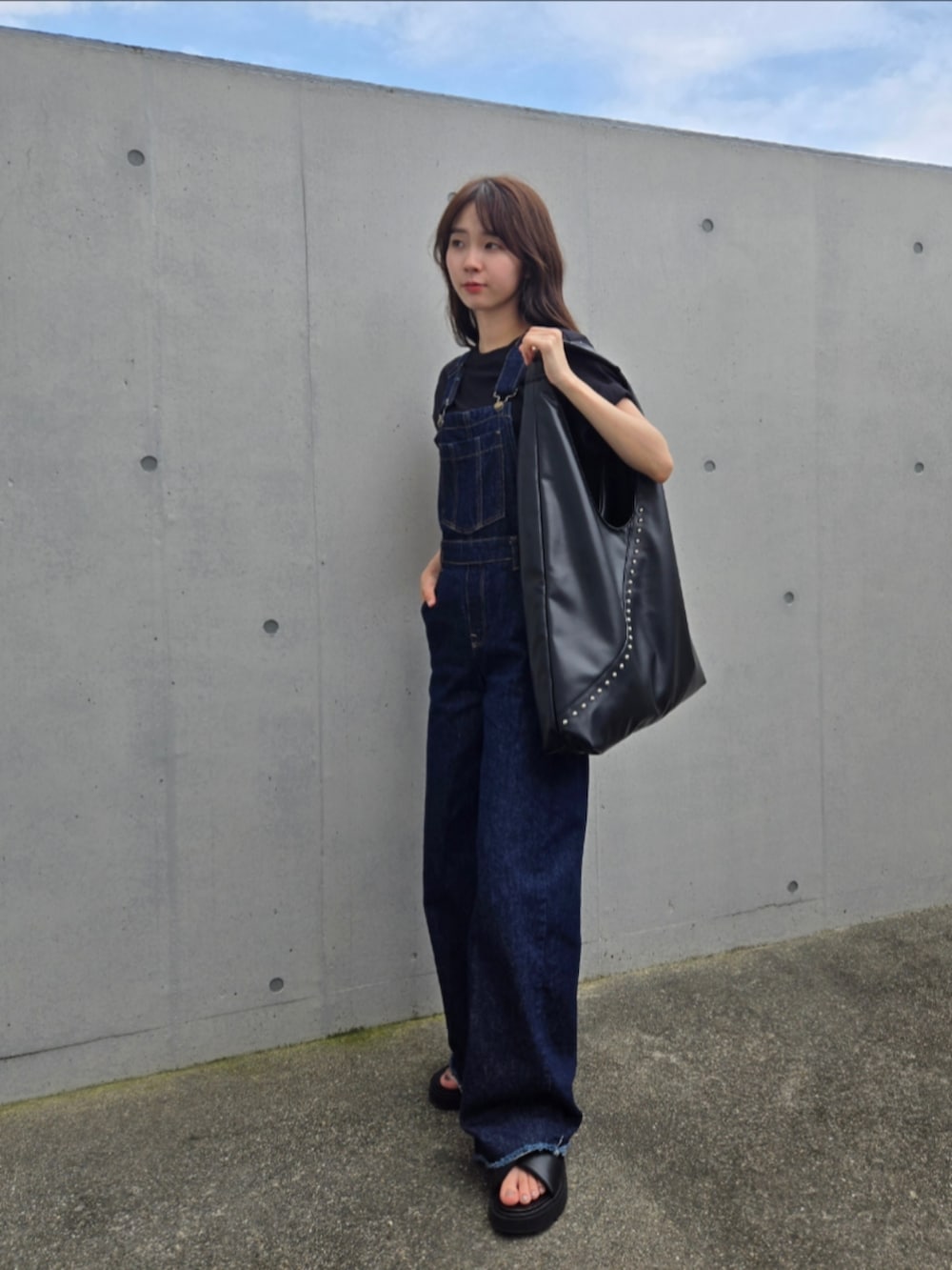 ブラック系のトートバッグ、ブルー系のサロペット/オーバーオール、ブラック系のサンダルを着用したレディースの夏コーディネートの3枚目の写真