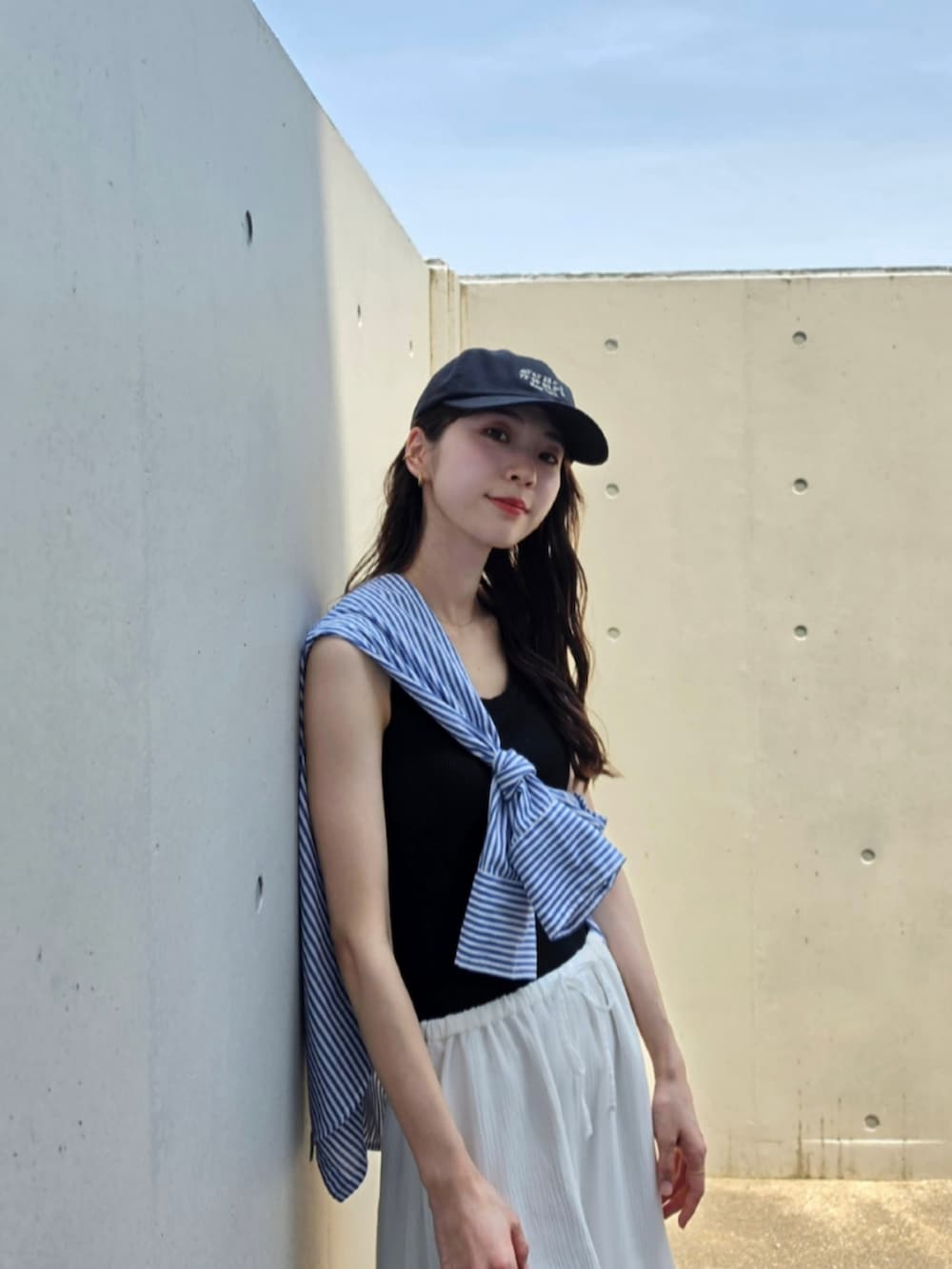 ブルー系のシャツ/ブラウス、ホワイト系のスカート、ブラック系のハンドバッグを着用したレディースの夏コーディネートの2枚目の写真
