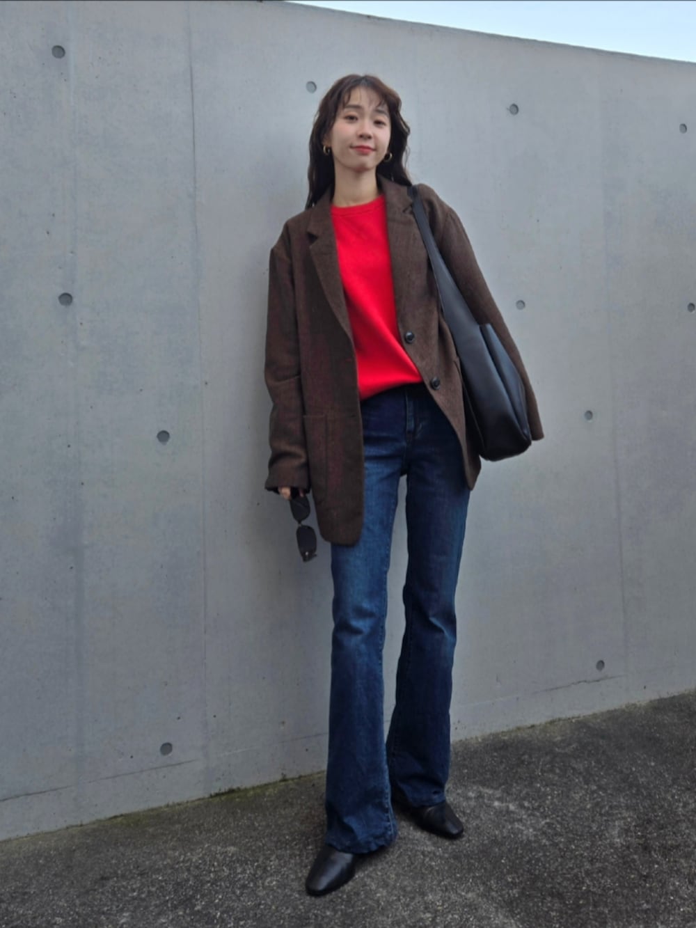 ブルー系のデニムパンツ、ブラック系のトートバッグ、ブラウン系のテーラードジャケットを着用したレディースの冬コーディネートの3枚目の写真