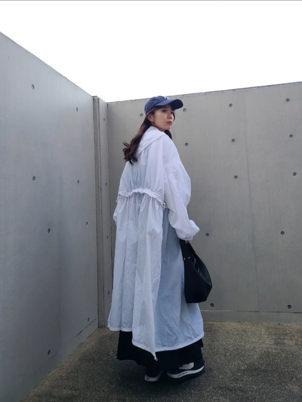 ブラック系のハンドバッグ、ホワイト系のナイロンジャケット、ブルー系のスニーカーを着用したレディースの春コーディネートの4枚目の写真