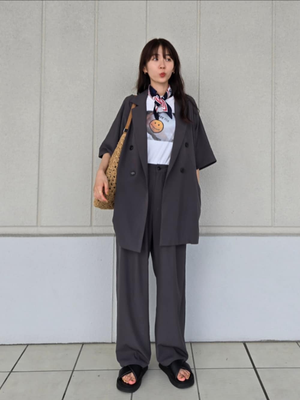 ブラック系のサンダル、ブラウン系のかごバッグ、グレー系のテーラードジャケットを着用したレディースの秋コーディネートの3枚目の写真