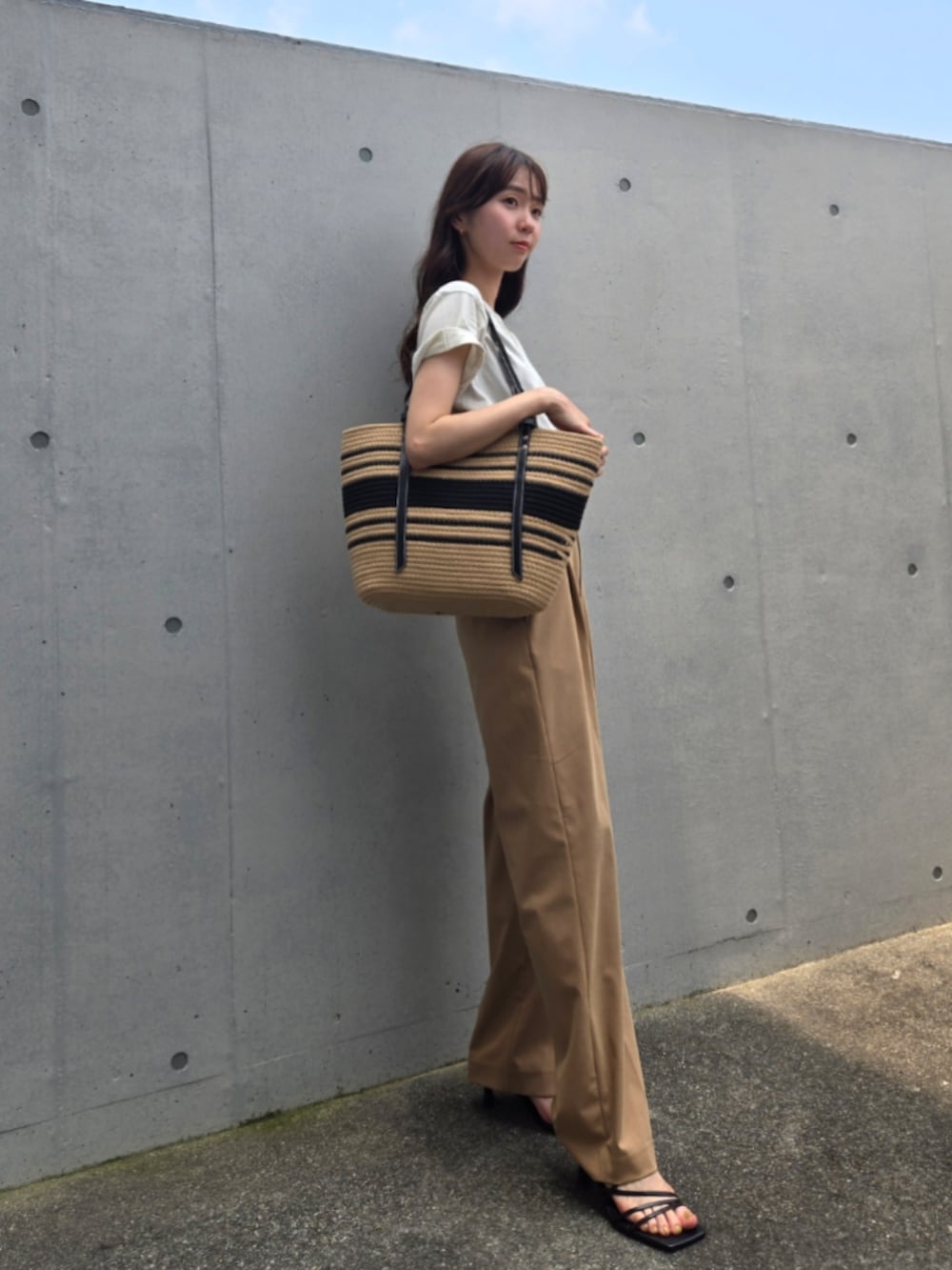 ベージュ系のかごバッグ、ベージュ系のTシャツ/カットソー、ベージュ系のパンツを着用したレディースの夏コーディネートの2枚目の写真