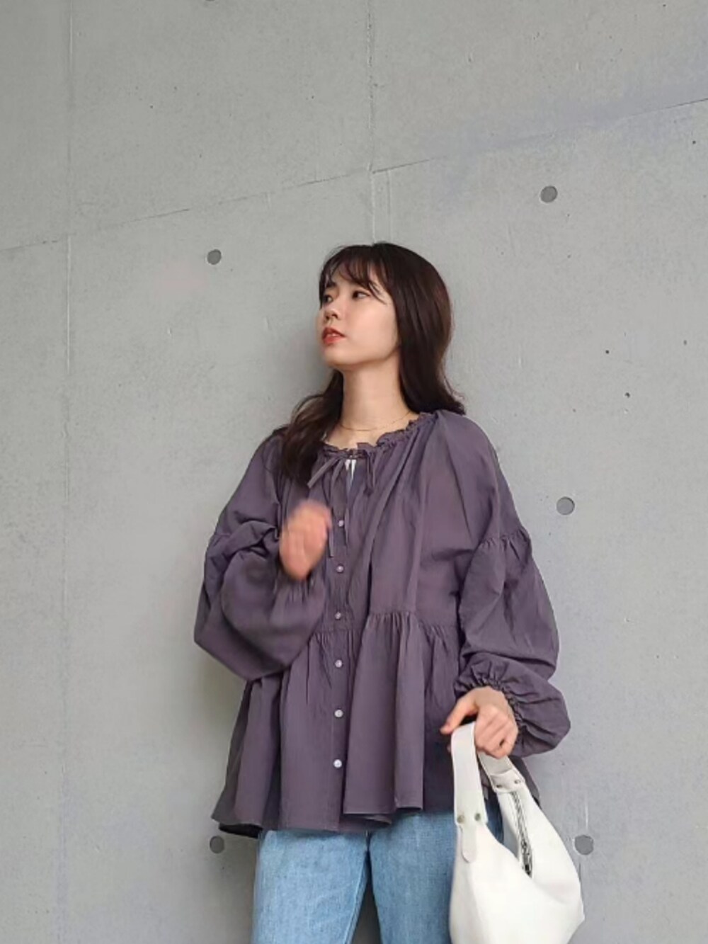 ブルー系のデニムパンツ、ホワイト系のハンドバッグ、ブラウン系のアイシャドウを着用したレディースの春コーディネートの3枚目の写真