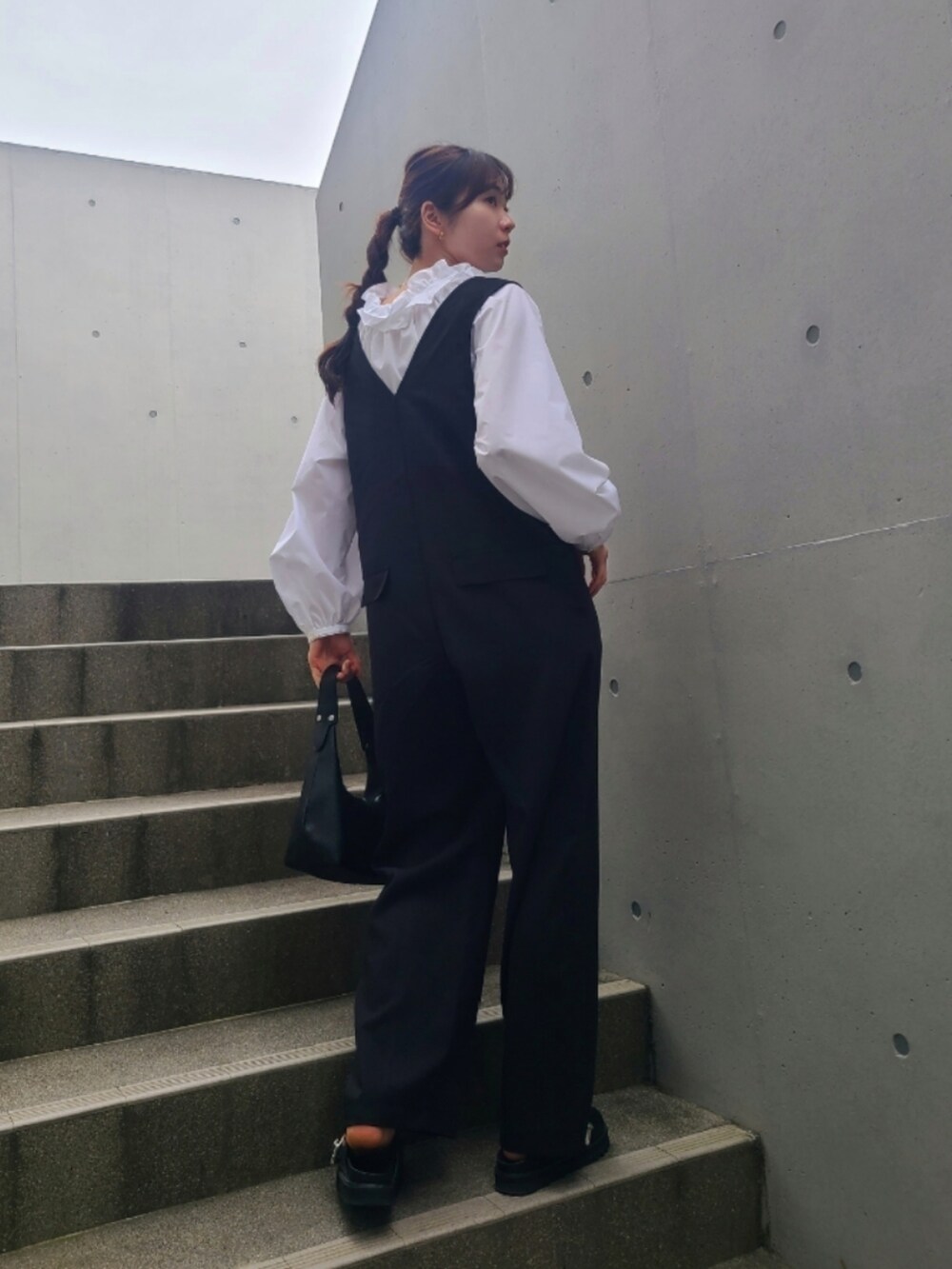 ブラック系のサンダル、ホワイト系のシャツ/ブラウス、ブラック系のサロペット/オーバーオールを着用したレディースの春コーディネートの3枚目の写真