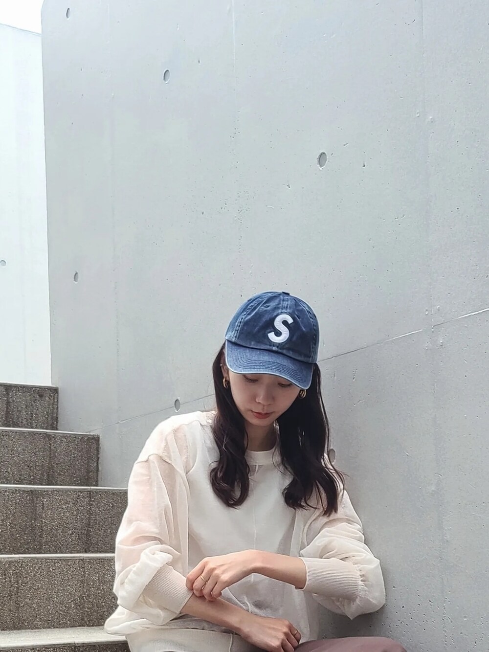 ホワイト系のカーディガン/ボレロ、ブルー系のキャップ、ゴールド系のピアス（両耳用）を着用したレディースの春コーディネートの3枚目の写真