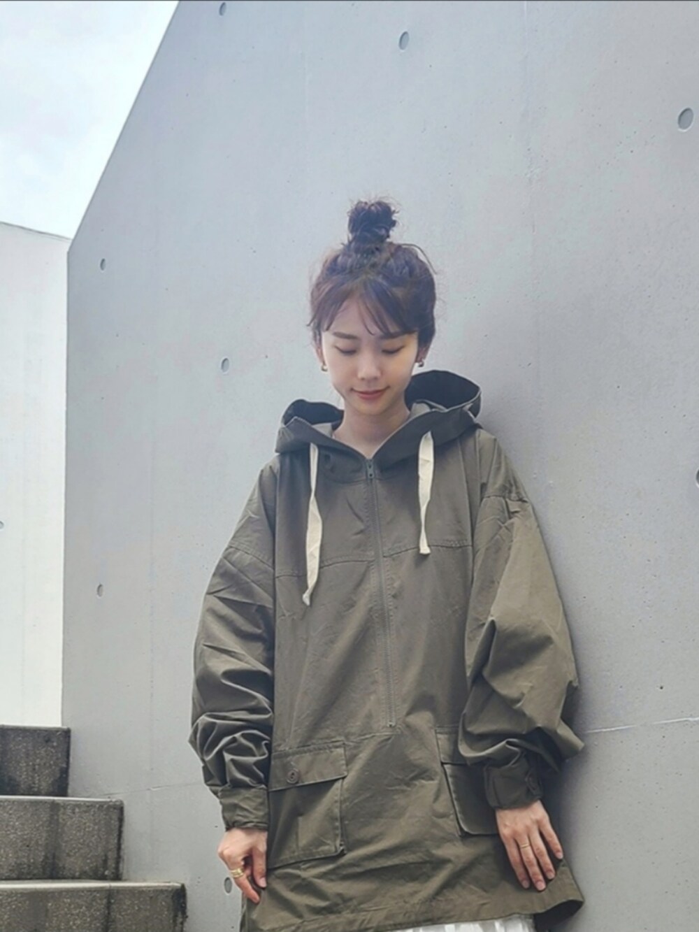 グリーン系のマウンテンパーカー、ブラック系のブーツ、ゴールド系のピアス（両耳用）を着用したレディースの夏コーディネートの3枚目の写真