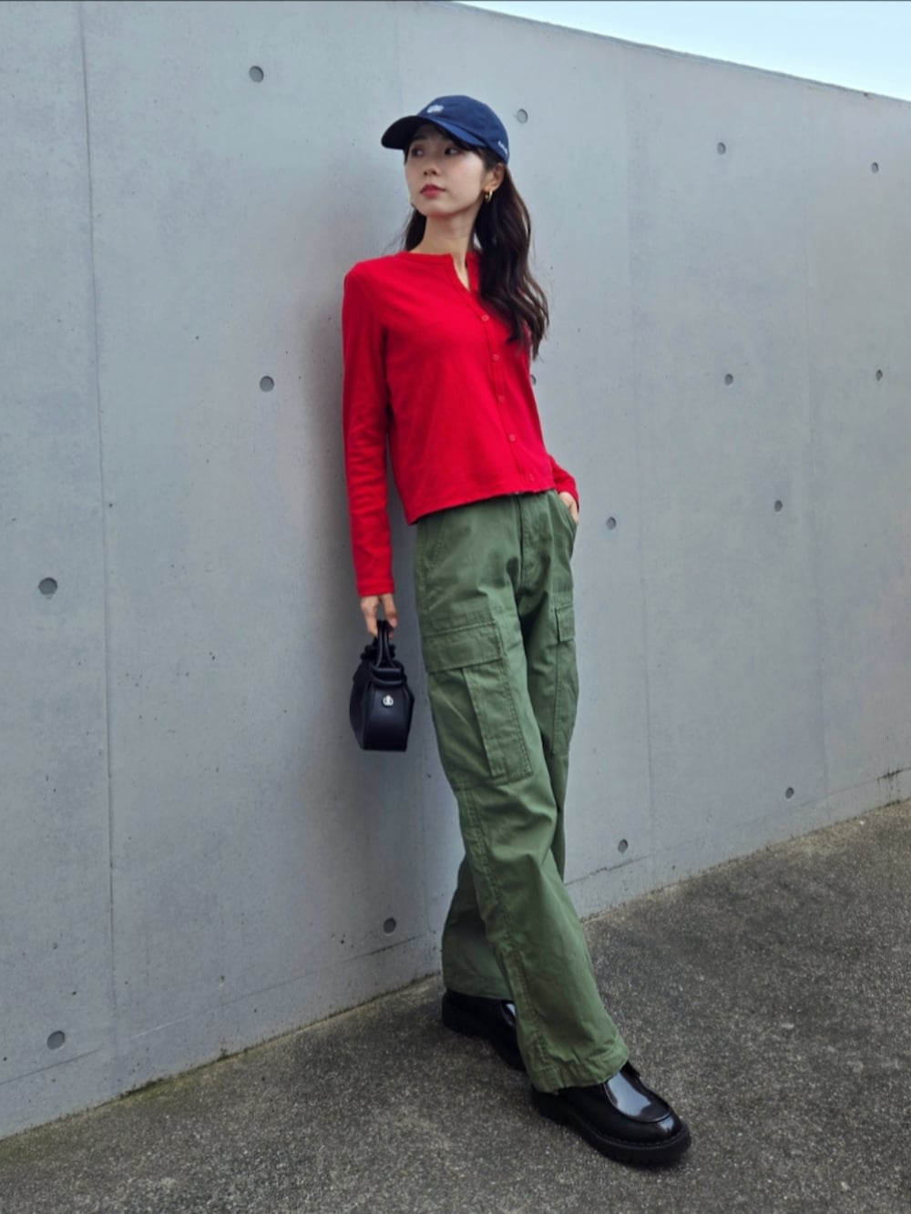 グリーン系のカーゴパンツ、レッド系のカーディガン/ボレロ、ブラック系のハンドバッグを着用したレディースの春コーディネートの2枚目の写真