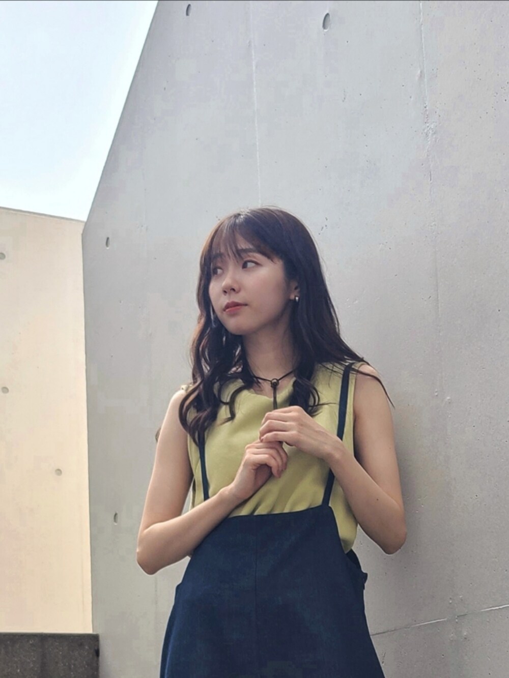 ブルー系のサロペット/オーバーオール、グリーン系のトップス、ホワイト系のサンダルを着用したレディースの春コーディネートの3枚目の写真