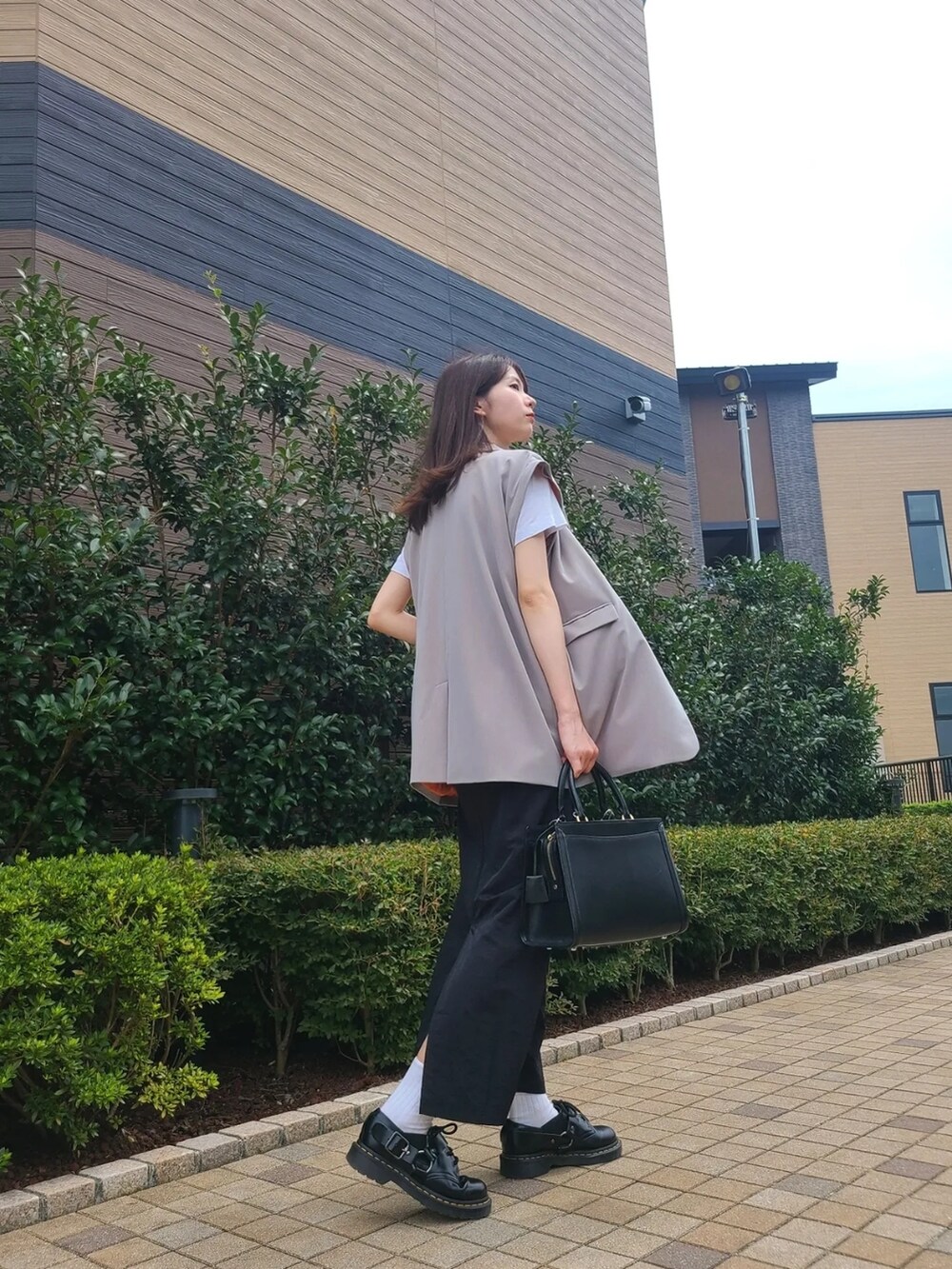 グレー系のテーラードジャケット、ブラック系のスカート、ブラック系のブーツを着用したレディースの夏コーディネートの2枚目の写真