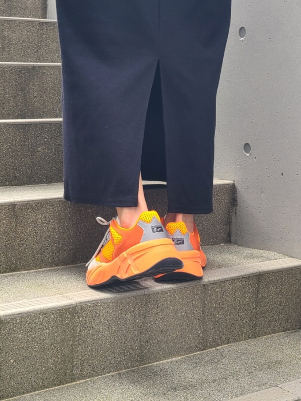 ブラック系のワンピース、オレンジ系のスニーカー、ブラック系のキャップを着用したレディースの秋コーディネートの2枚目の写真