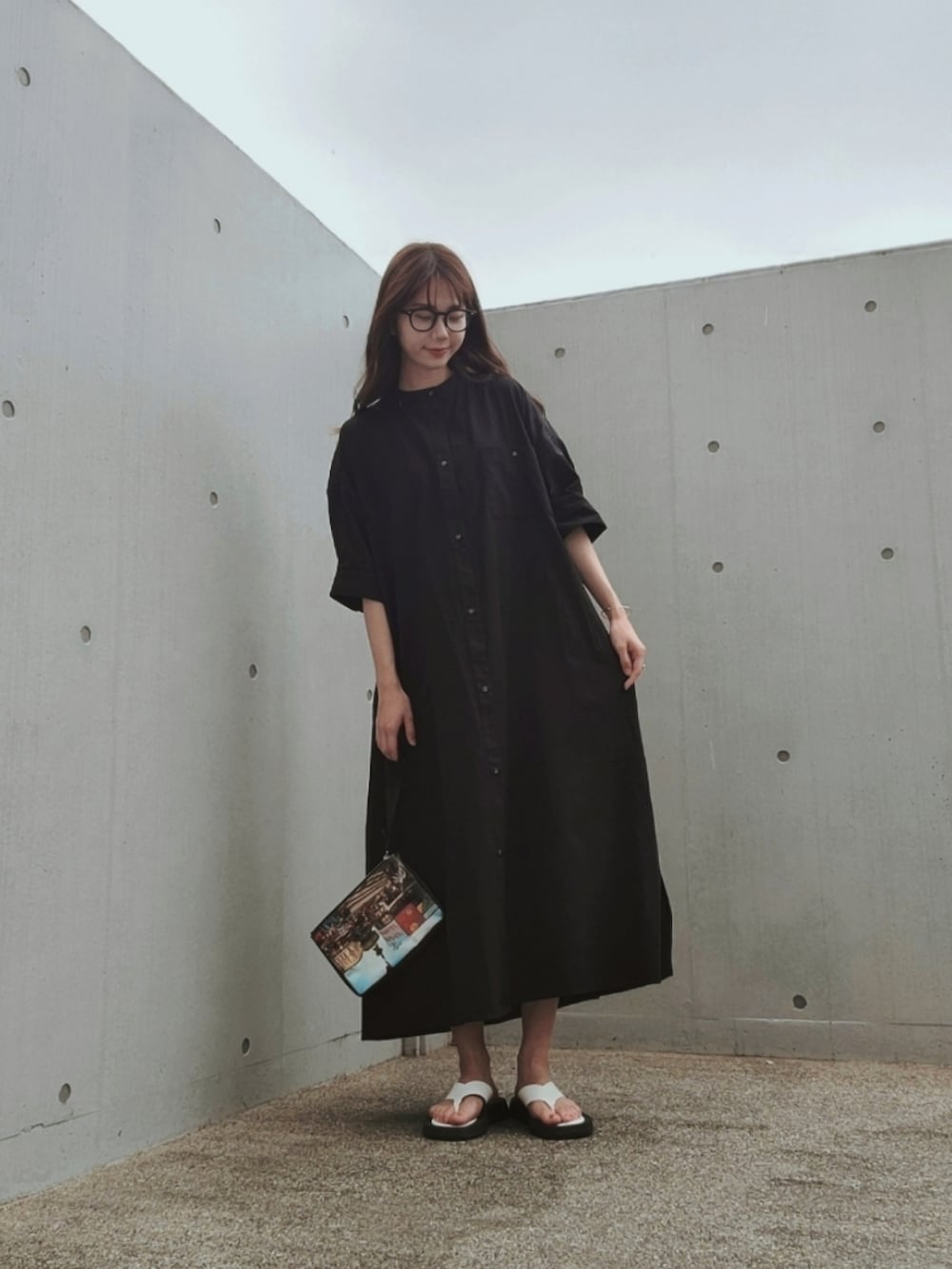 ブラック系のシャツワンピース、その他のバッグ、ホワイト系のサンダルを着用したレディースの夏コーディネートの2枚目の写真