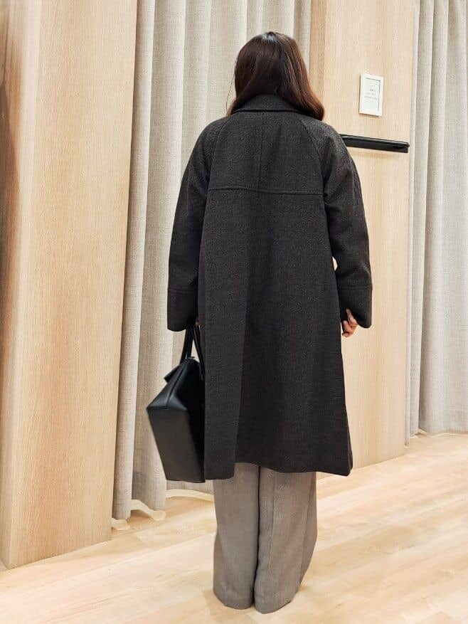 グレー系のステンカラーコート、ホワイト系のニット/セーター、グレー系のその他パンツを着用したレディースの秋コーディネートの4枚目の写真