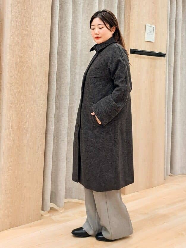 グレー系のステンカラーコート、ホワイト系のニット/セーター、グレー系のその他パンツを着用したレディースの秋コーディネートの3枚目の写真