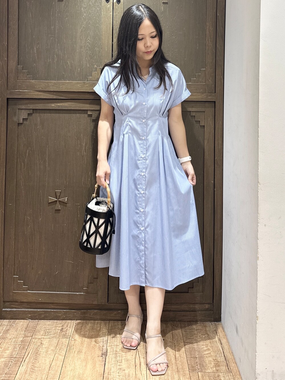 ブルー系のワンピース、ブラック系のハンドバッグ、ベージュ系のサンダルを着用したレディースの夏コーディネートの6枚目の写真