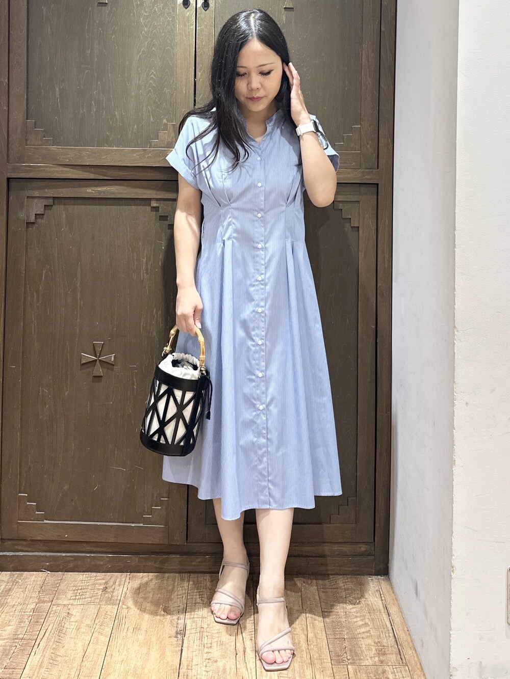 ブルー系のワンピース、ブラック系のハンドバッグ、ベージュ系のサンダルを着用したレディースの夏コーディネートの4枚目の写真