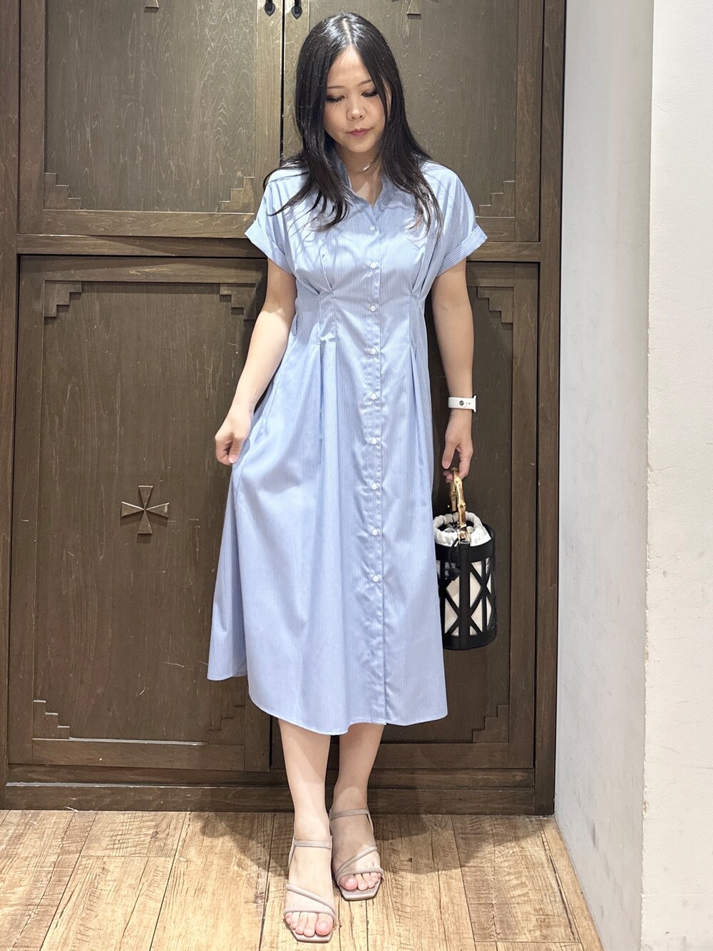 ブルー系のワンピース、ブラック系のハンドバッグ、ベージュ系のサンダルを着用したレディースの夏コーディネートの2枚目の写真