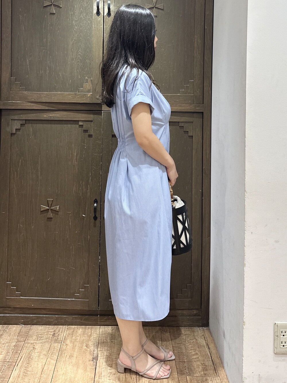 ブルー系のワンピース、ブラック系のハンドバッグ、ベージュ系のサンダルを着用したレディースの夏コーディネートの7枚目の写真