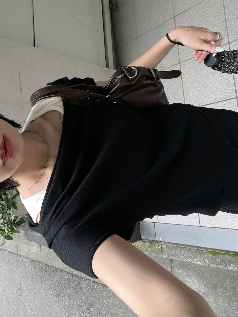 ブラック系のデニムパンツ、ブラウン系のトートバッグ、ブラック系のTシャツ/カットソーを着用したレディースの夏コーディネートの2枚目の写真