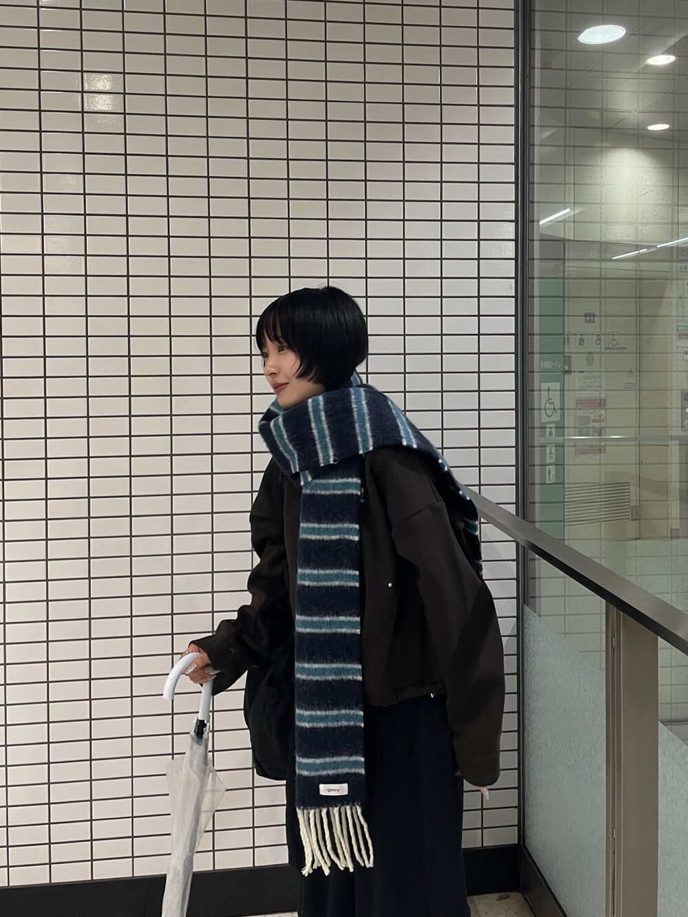 ブラウン系のブルゾン、ブラック系のその他パンツ、ブルー系のマフラーを着用したレディースの秋コーディネートの5枚目の写真