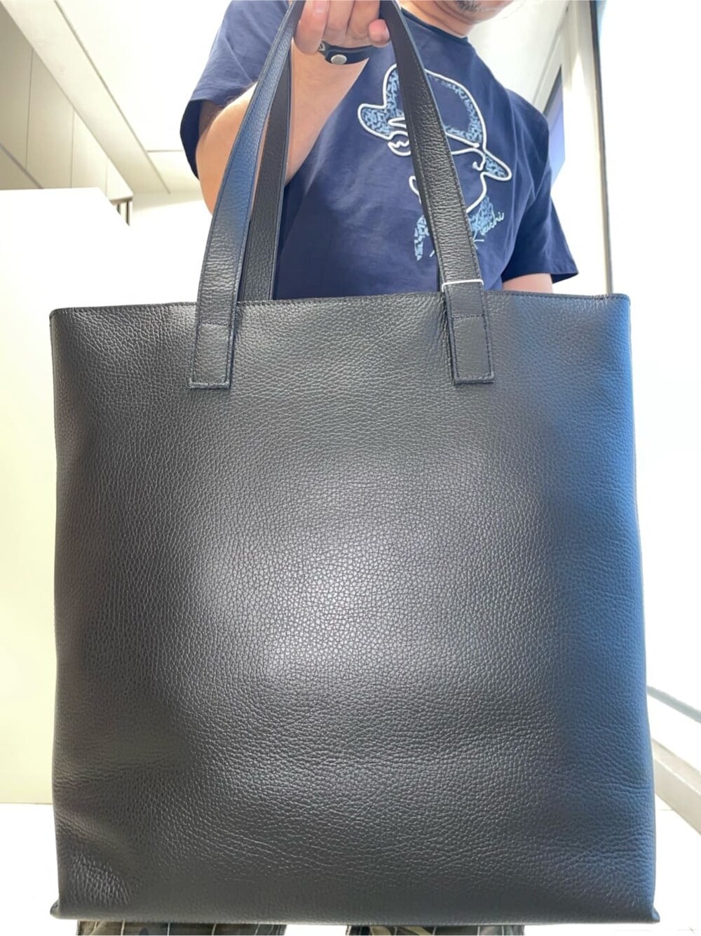 ブルー系のTシャツ/カットソー、ブラック系のトートバッグ、グリーン系のハットを着用したメンズの夏コーディネートの9枚目の写真