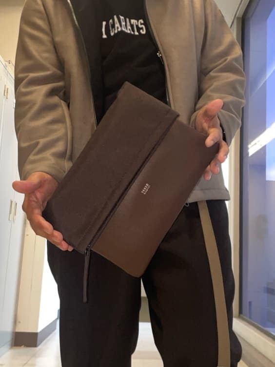 ベージュ系のブルゾン、ブラウン系のクラッチバッグ、ブラウン系のスニーカーを着用したメンズの秋コーディネートの8枚目の写真