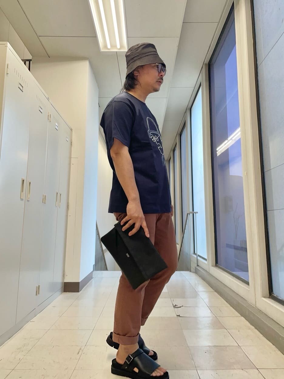 ブラック系のクラッチバッグ、ブルー系のTシャツ/カットソーを着用したメンズの春コーディネートの3枚目の写真