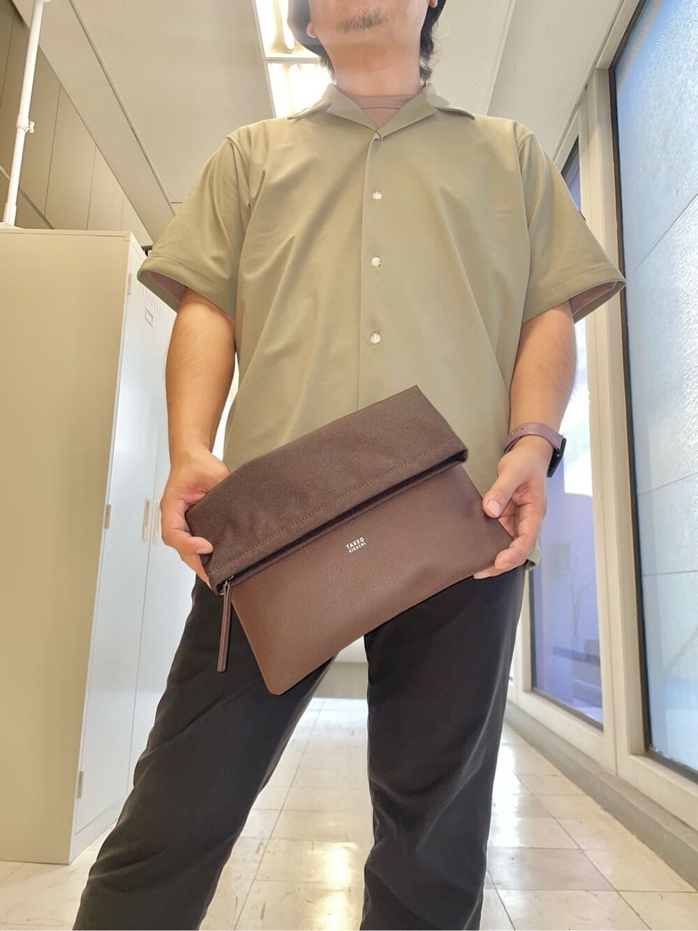 グリーン系のシャツ/ブラウス、ブラウン系のクラッチバッグを着用したメンズの秋コーディネートの7枚目の写真
