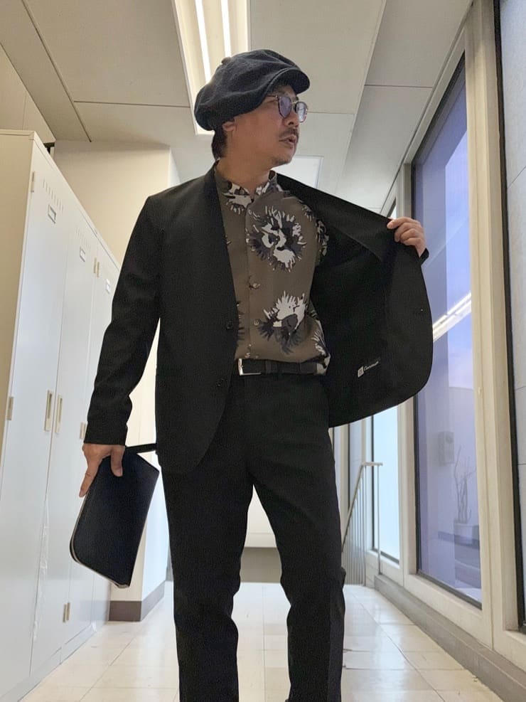 ブラック系のノーカラージャケット、ブラック系のスラックス、ブラック系のクラッチバッグを着用したメンズの冬コーディネートの5枚目の写真
