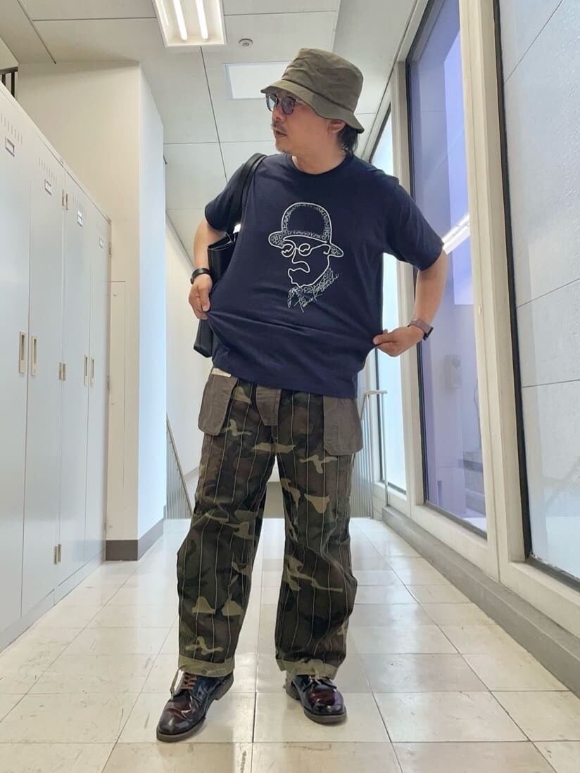 ブルー系のTシャツ/カットソー、ブラック系のトートバッグ、グリーン系のハットを着用したメンズの夏コーディネートの7枚目の写真