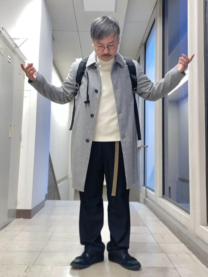グレー系のステンカラーコート、ホワイト系のTシャツ/カットソー、ブラック系のバックパック/リュックを着用したメンズの秋コーディネートの4枚目の写真