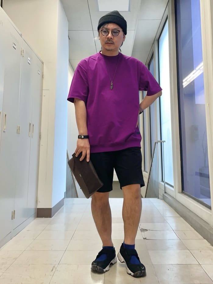 パープル系のTシャツ/カットソー、ブラウン系のクラッチバッグ、ブラック系のニットキャップ/ビーニーを着用したメンズの夏コーディネートの2枚目の写真