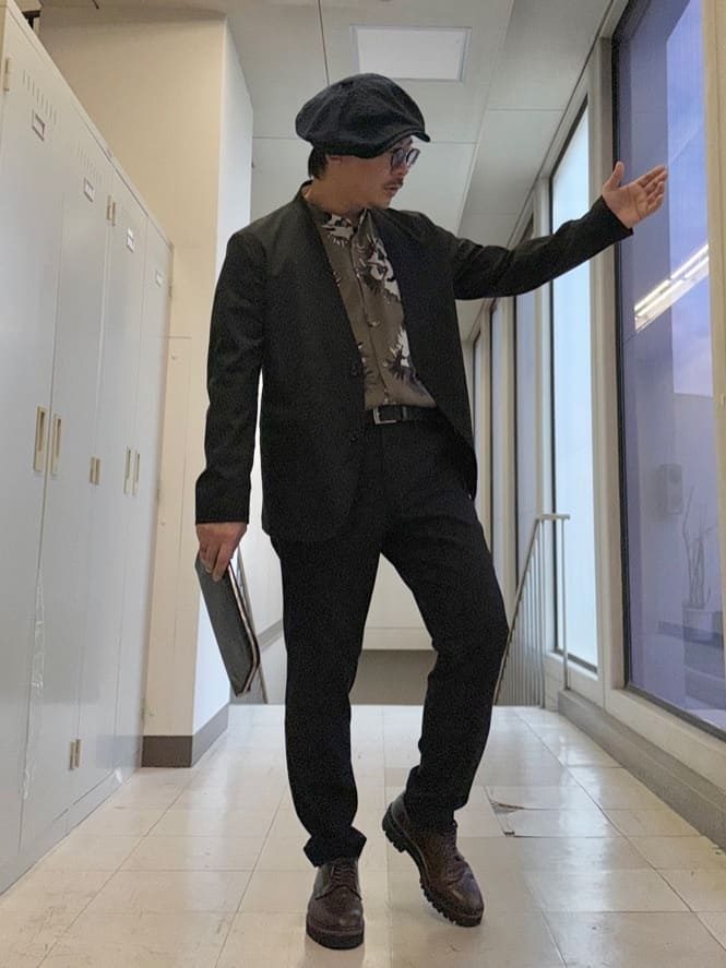 ブラック系のノーカラージャケット、ブラック系のスラックス、ブラック系のクラッチバッグを着用したメンズの冬コーディネートの8枚目の写真