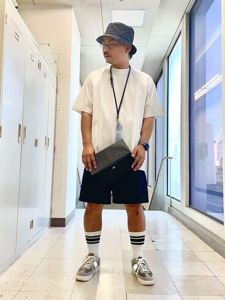 ブルー系のその他パンツ、グレー系のクラッチバッグ、ブルー系のハットを着用したメンズの夏コーディネートの2枚目の写真