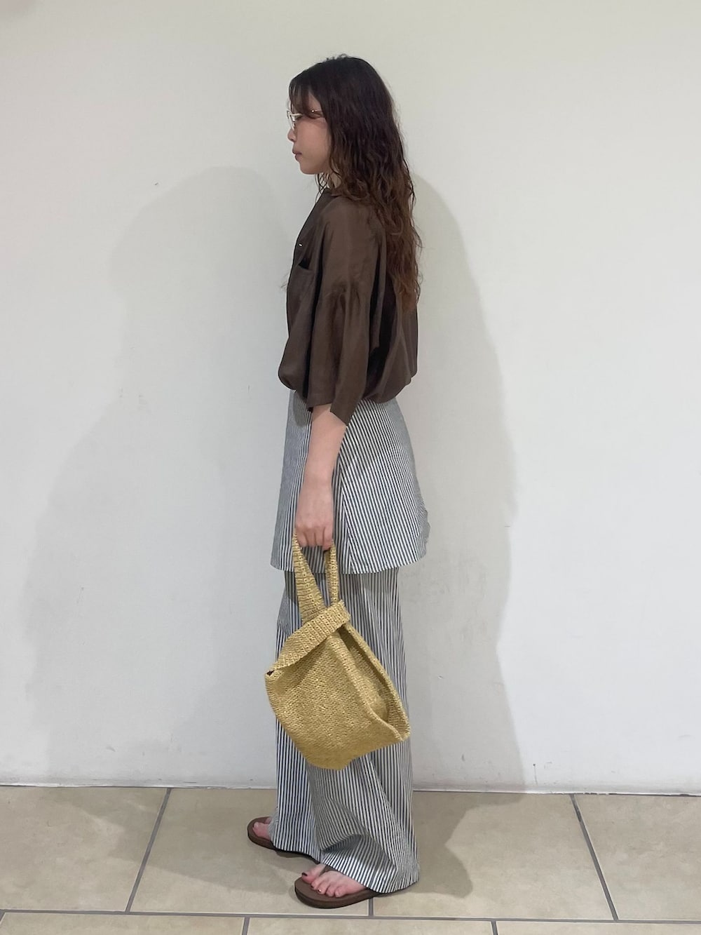 ホワイト系のその他パンツ、ブラウン系のシャツ/ブラウス、ホワイト系のかごバッグを着用したレディースの夏コーディネートの2枚目の写真