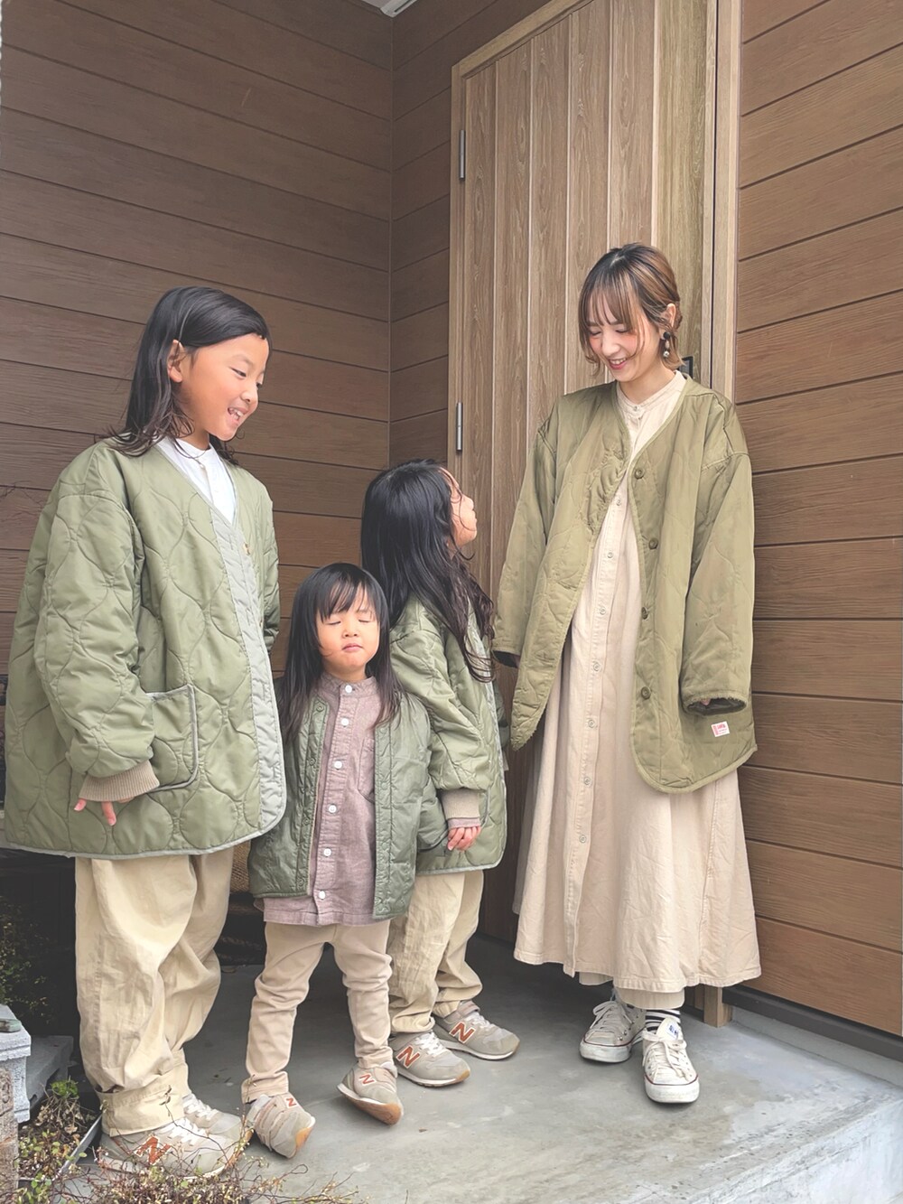 ベージュ系のワンピース、ブラウン系のノーカラージャケット、ホワイト系のスニーカーを着用したキッズの冬コーディネートの2枚目の写真