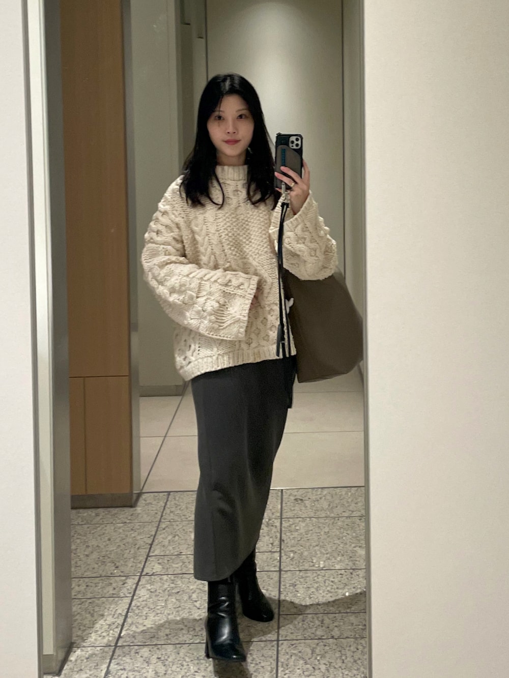 ホワイト系のニット/セーター、グレー系のスカート、ブラック系のブーツを着用したレディースの秋コーディネートの2枚目の写真
