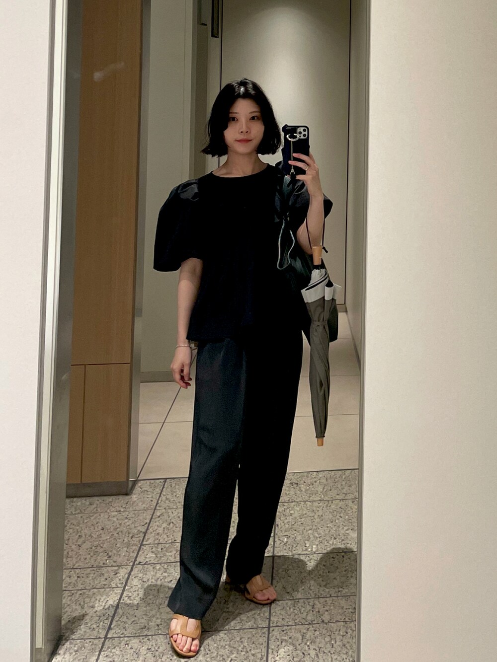 ブラック系のシャツ/ブラウス、グレー系のスラックス、ブラウン系のサンダルを着用したレディースの夏コーディネートの2枚目の写真