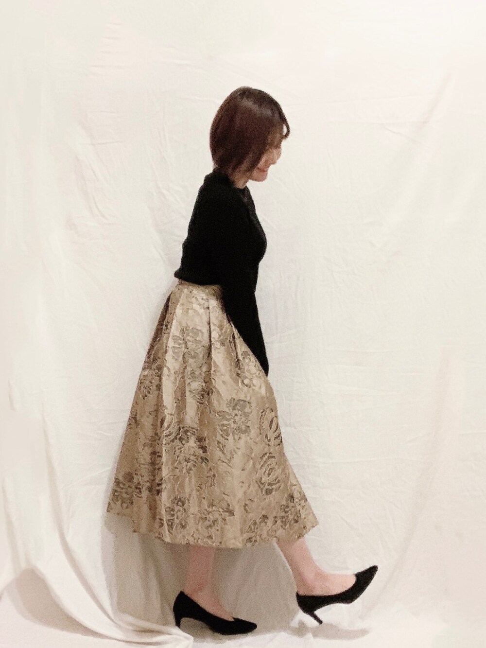 ブラック系のニット/セーター、ベージュ系のスカート、ブラック系のパンプスを着用したレディースの冬コーディネートの2枚目の写真