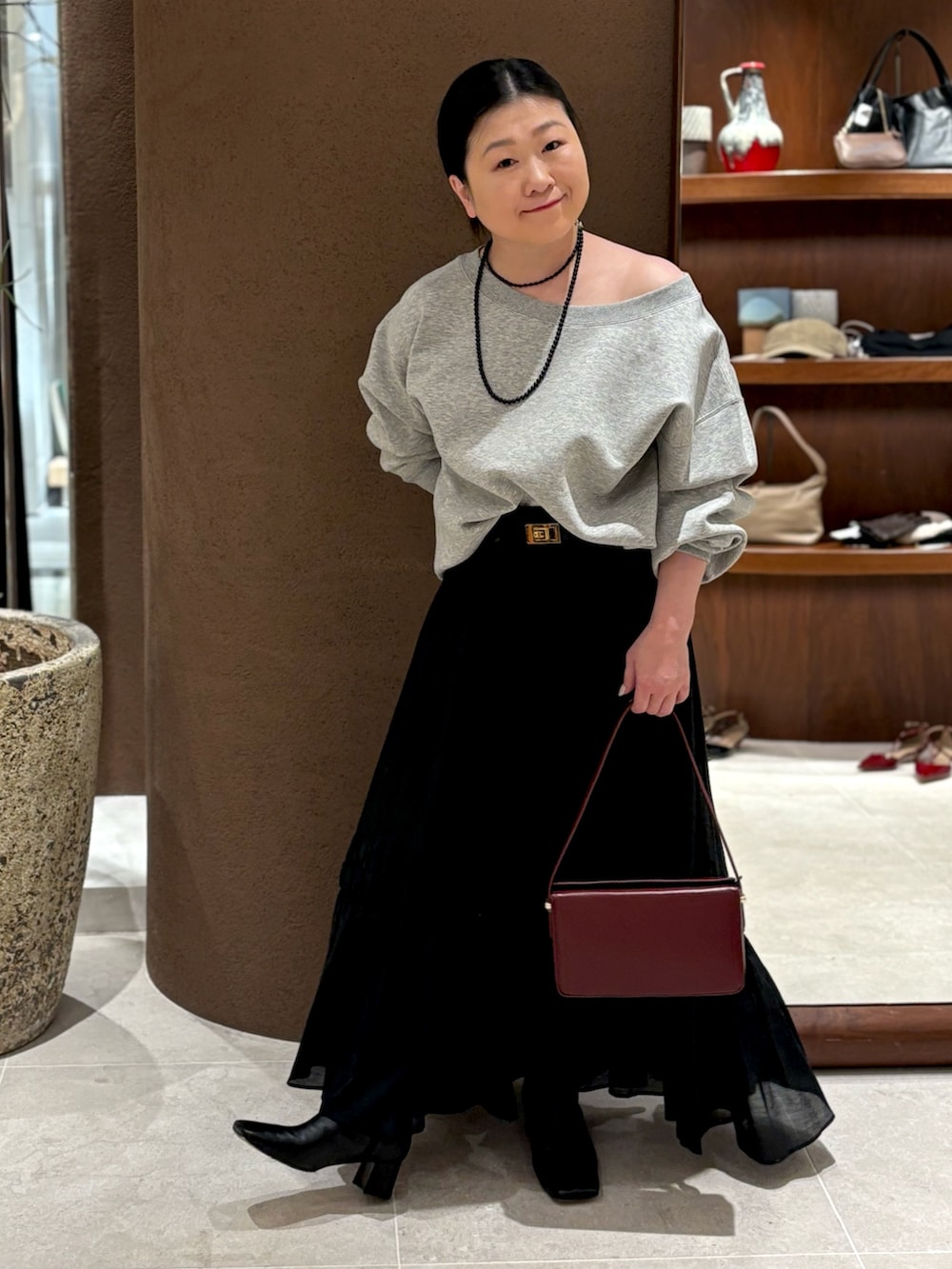 グレー系のTシャツ/カットソー、レッド系のショルダーバッグ、ブラック系のブーツを着用したレディースの冬コーディネートの3枚目の写真