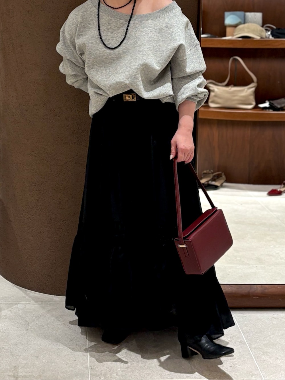 グレー系のTシャツ/カットソー、レッド系のショルダーバッグ、ブラック系のブーツを着用したレディースの冬コーディネートの2枚目の写真