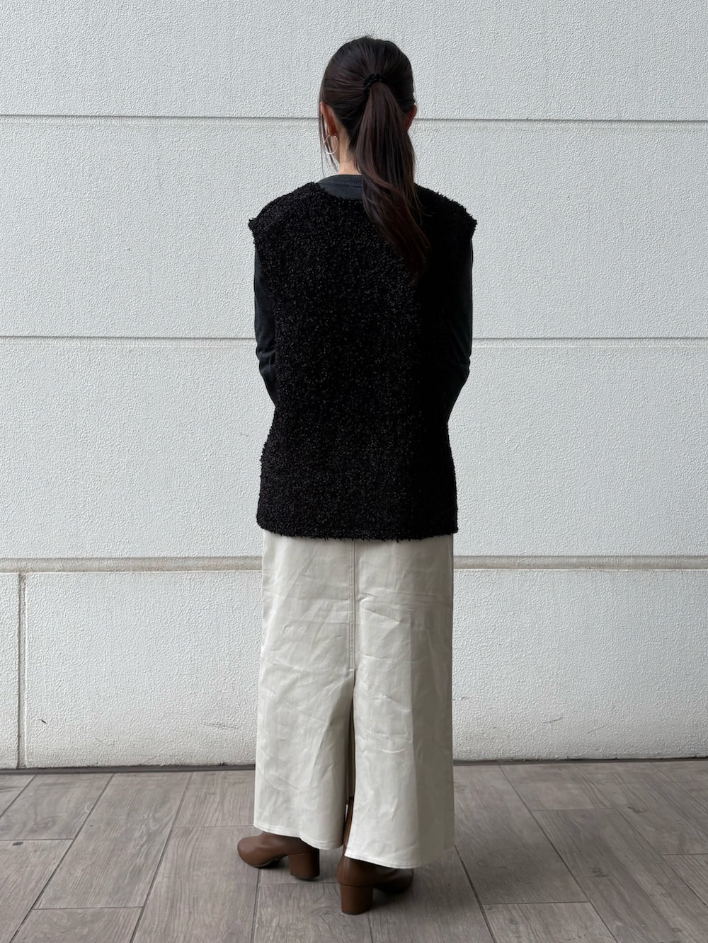 ブラック系のハンドバッグ、ベージュ系のスカート、ブラック系のニット/セーターを着用したレディースの冬コーディネートの3枚目の写真