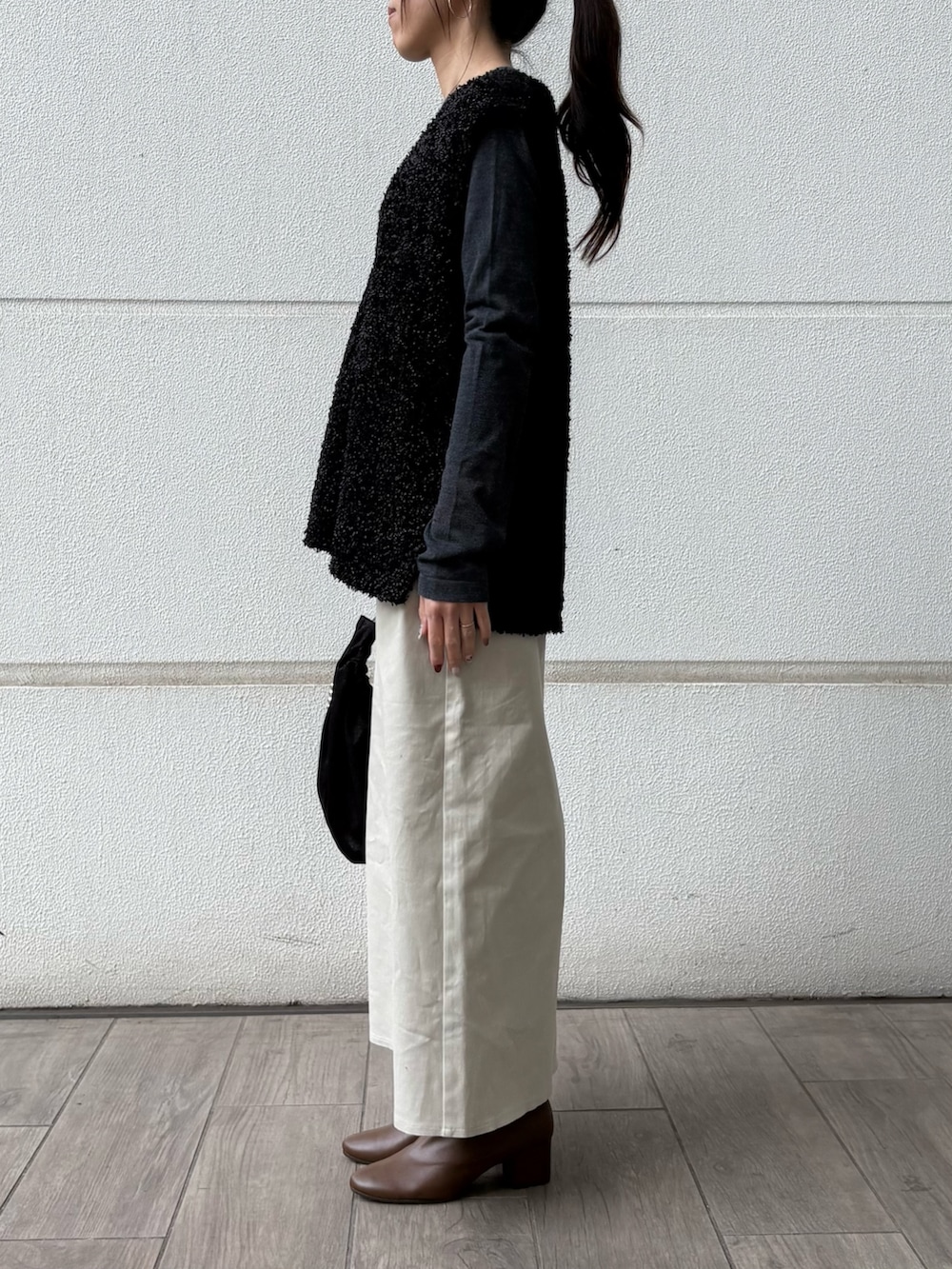 ブラック系のハンドバッグ、ベージュ系のスカート、ブラック系のニット/セーターを着用したレディースの冬コーディネートの2枚目の写真