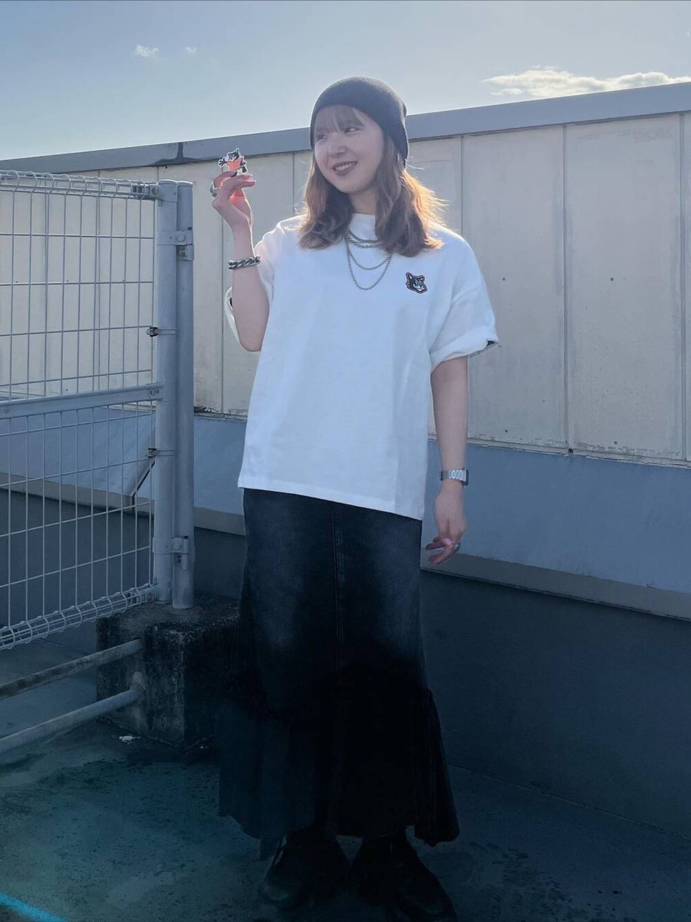 ブラック系のブーツ、ブラック系のデニムスカート、ホワイト系のTシャツ/カットソーを着用したレディースの春コーディネートの2枚目の写真