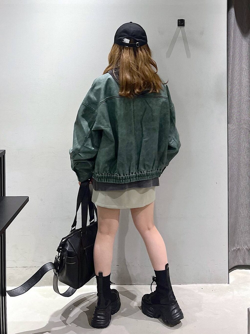 ブラック系のブーツ、ブラック系のボストンバッグ、グレー系のパーカーを着用したレディースの秋コーディネートの3枚目の写真